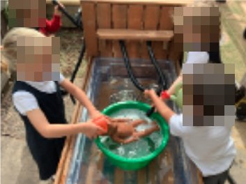 Children washing a doll in a water tray